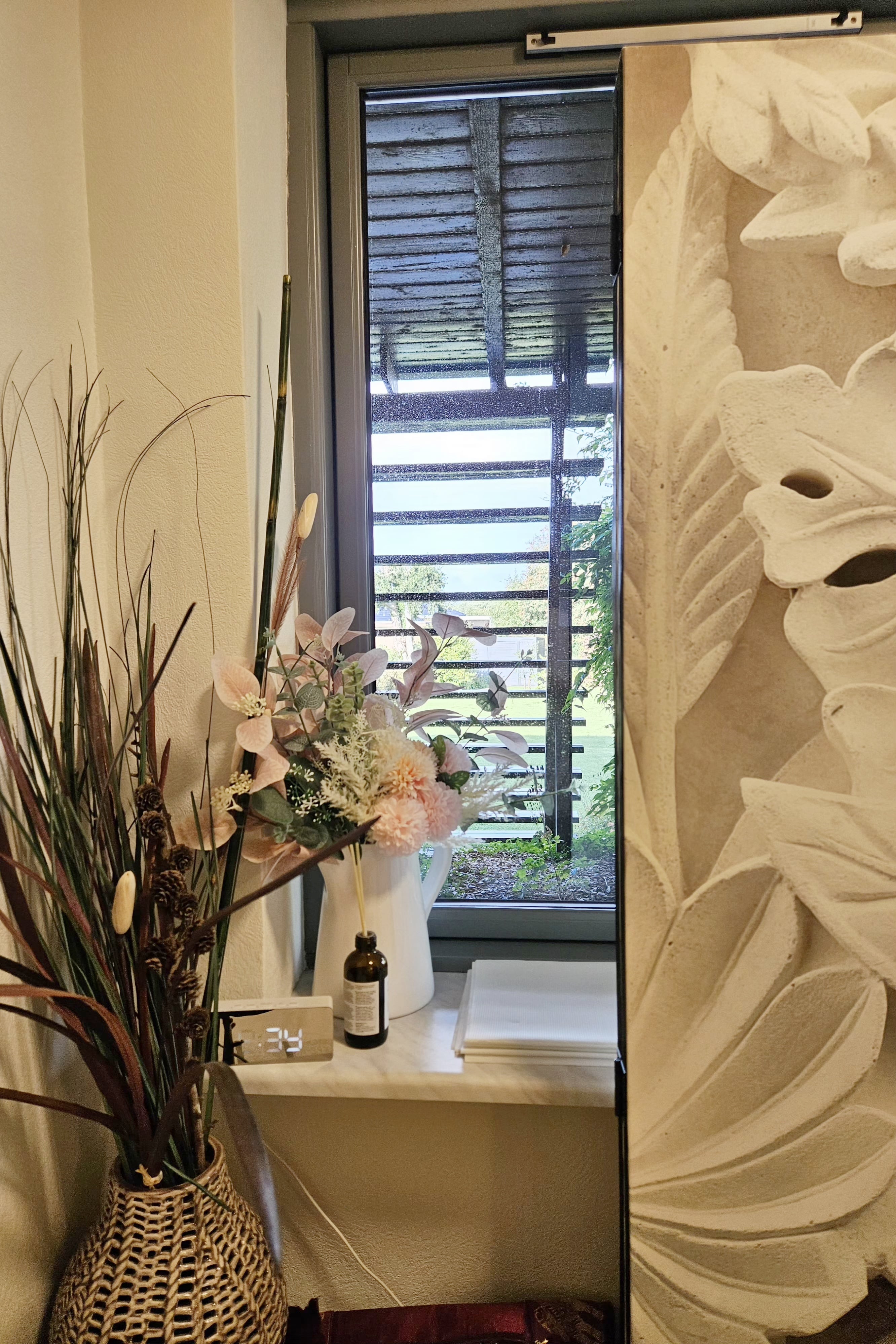 Et billede af en vase med blomster ved vinduet
